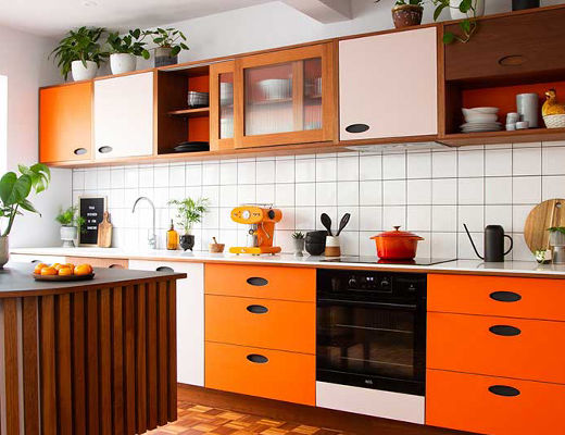 Orange wooden kitchen with white splashback and pink accents